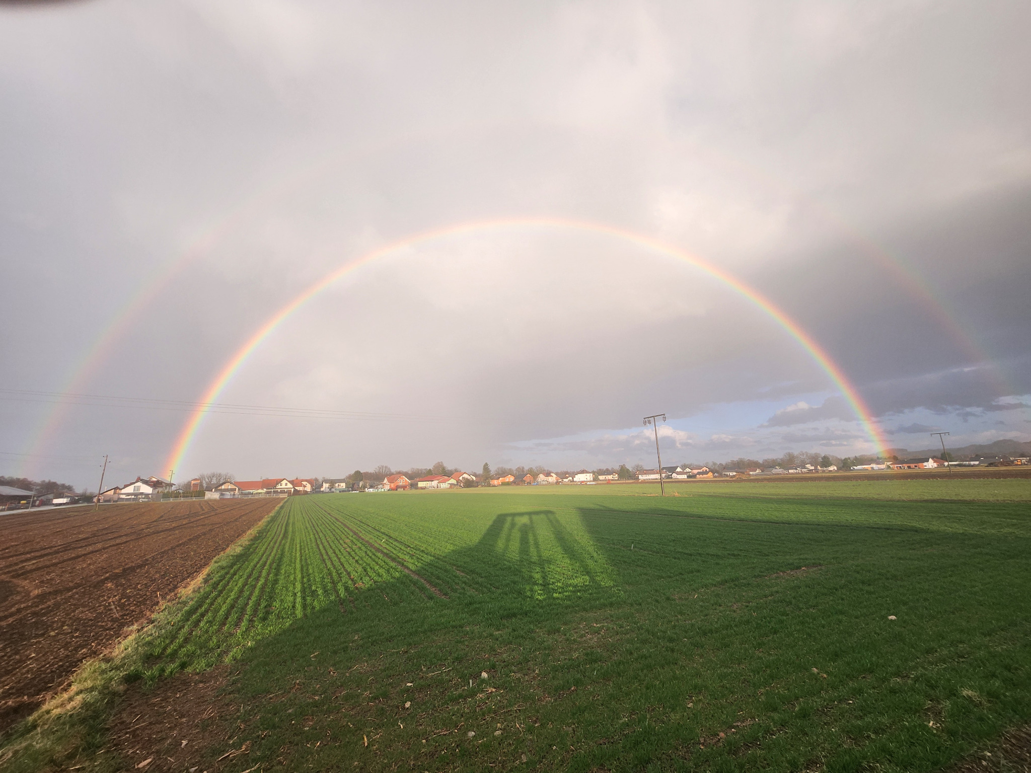 Mavrica nad kmetijsko pokrajino po neurju